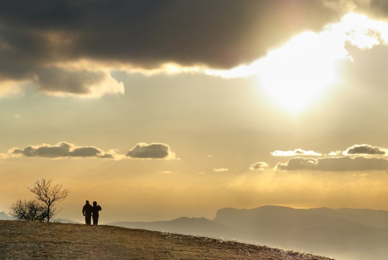 Couple on a hill at sunset overlooking the mountains is a great date idea