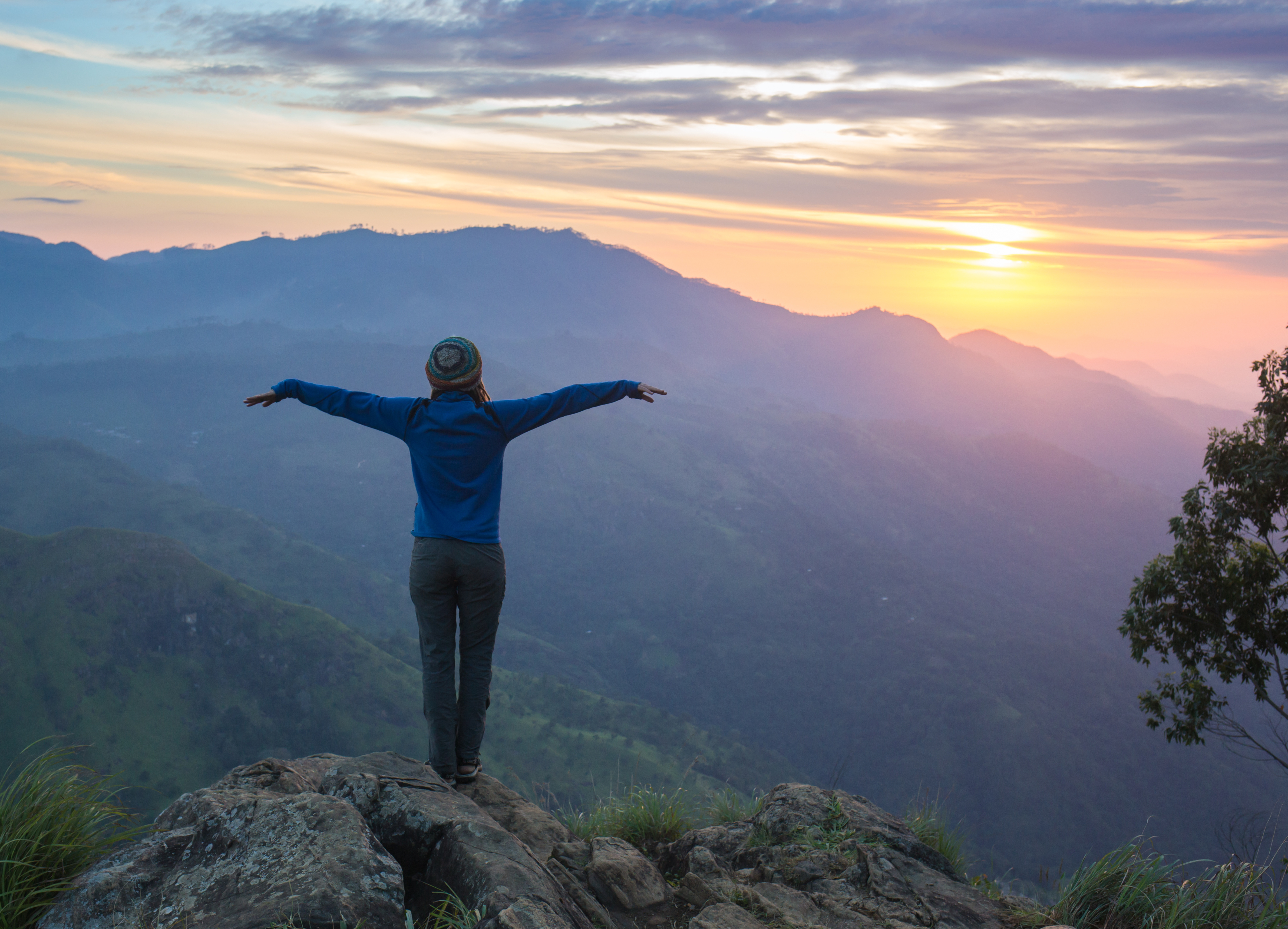 Woman traveling alone celebrating her hike at the top of a mountain