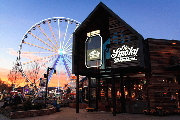 Entrance to Ole Smoky lit up with the wheel at the island and a sunset visible in background.