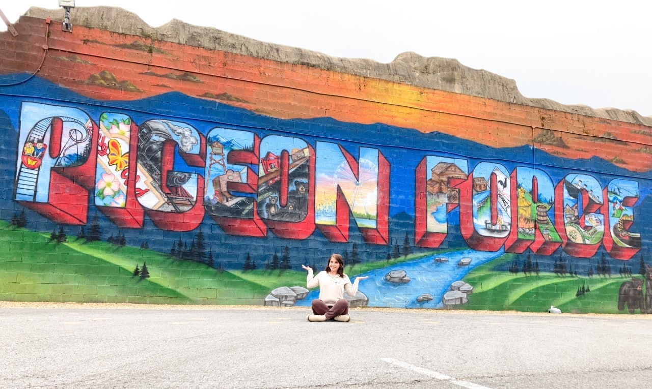 Woman in front of mural that says "Pigeon Forge" with a smoky mountain scene
