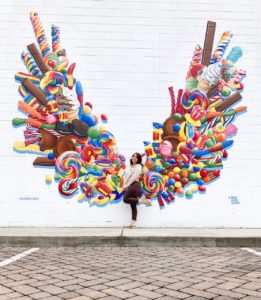 Woman standing in front of a mural of wings made of candy 