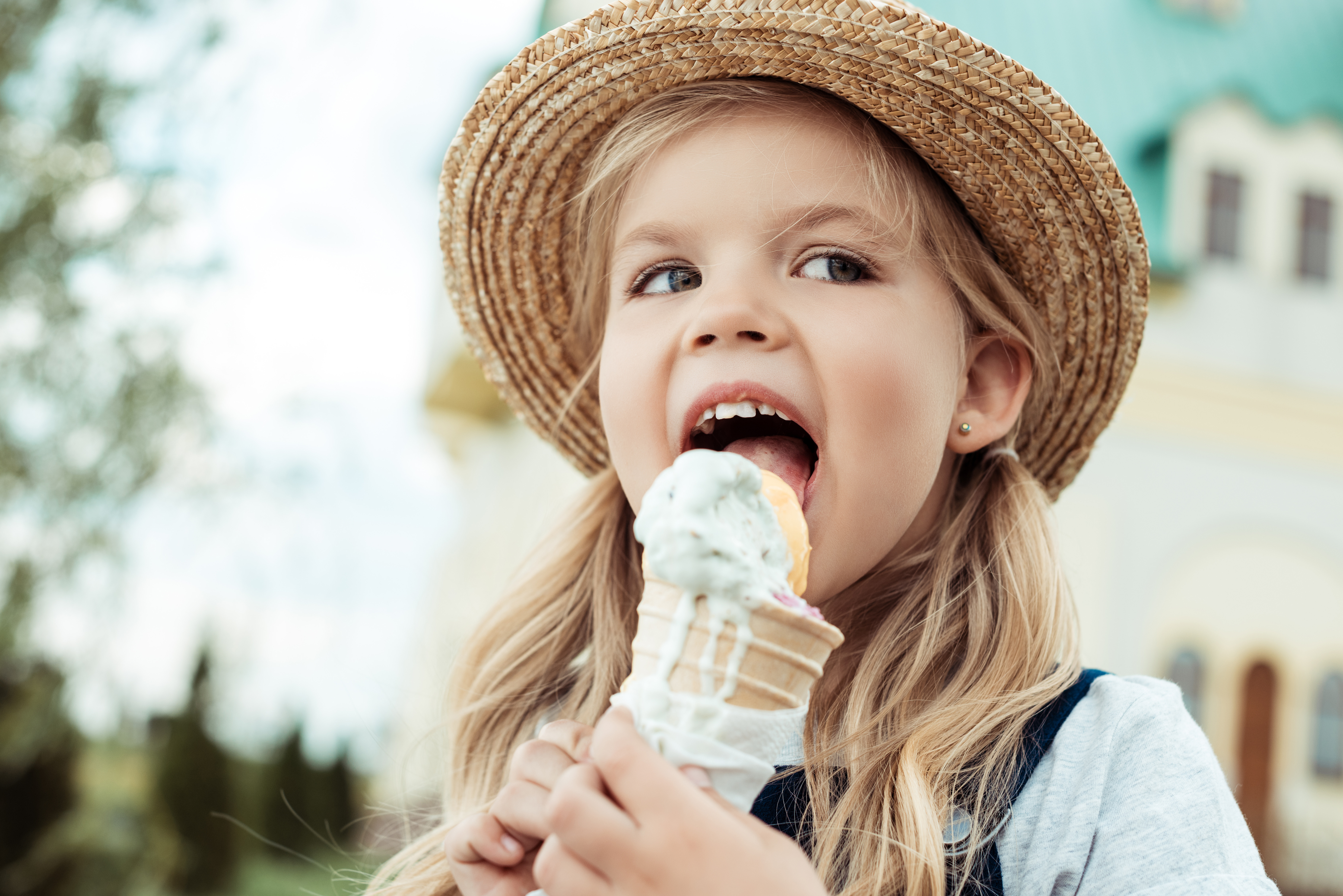 portrait of little girl in straw hat eating ice cream