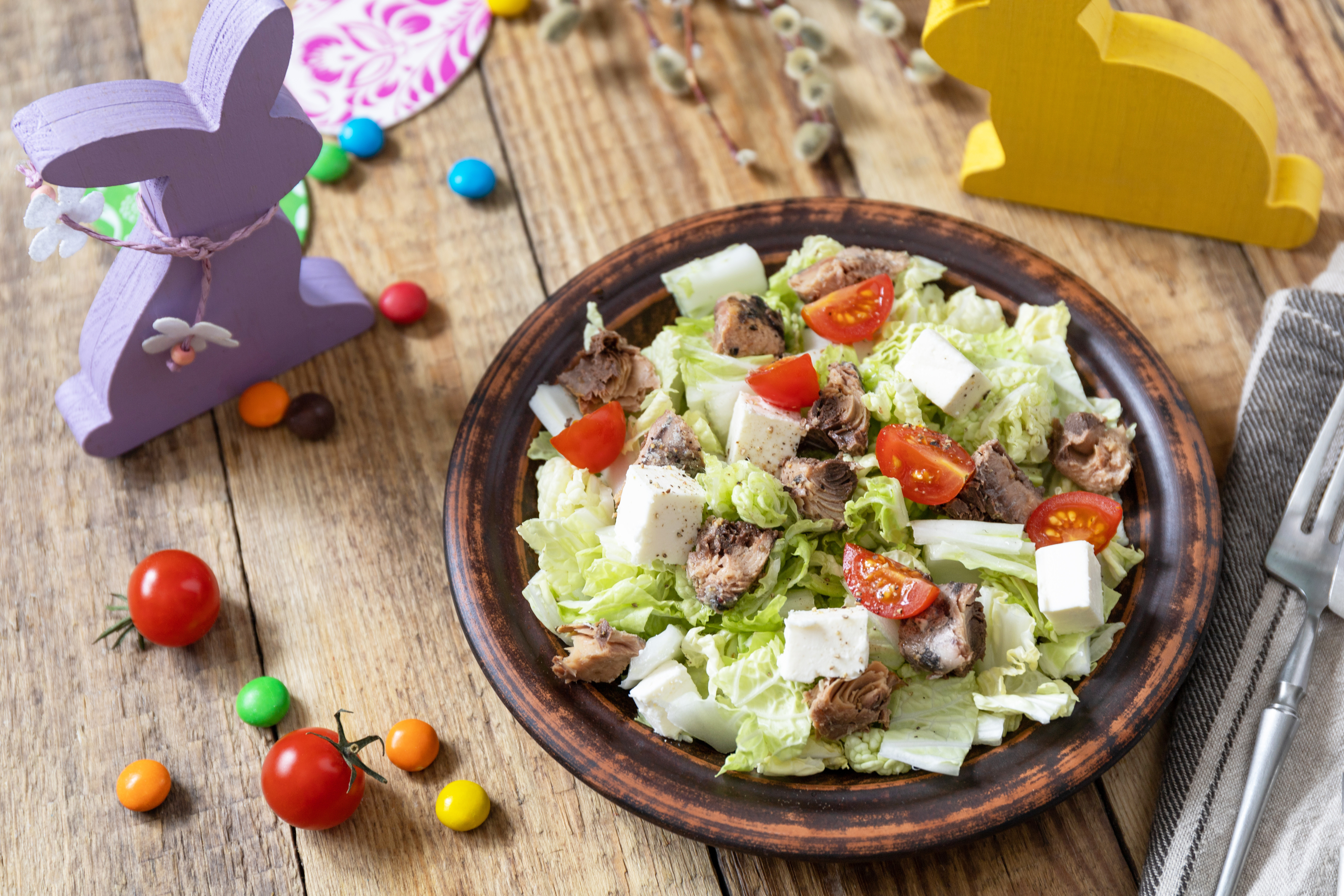 Holiday food, easter salad. Salad with chinese cabbage, feta, cherry tomatoes and canned tuna and vinegar dressing on a festive table.