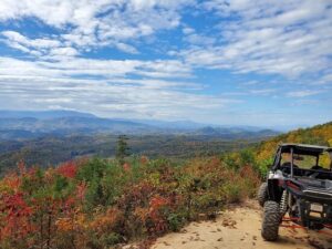 An ATV parked by the side of a bluff and a view of the Smokies in the background. 